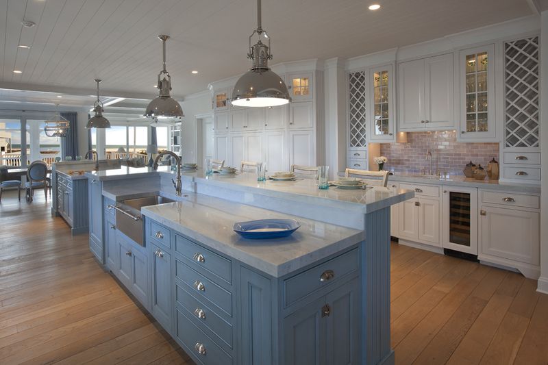 Raised eating area above large island with baby blue cabinets and stainless steel farmhouse sink.