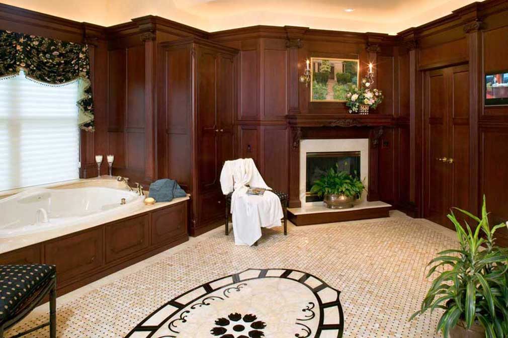 Large formal master bath design with dark wood cabinets and crown molding with a fireplace