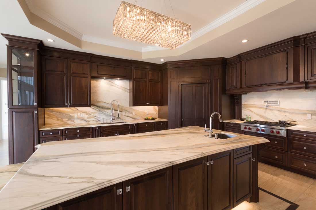 cocoa walnut kitchen design with a large island and marble countertops with matching marble backsplash